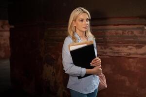 Enthusiastic Serious beautiful young girl holding pile of books standing near campus lifestyle positivity academic graduating university school photo