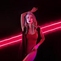 Fashion art photo of elegant model in seductive red swimsuit with light neon colored club spotlights Night club sexy concept