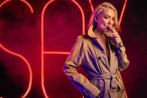 Young blondie woman smoking a cigarette wearing the beige coat photo