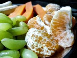 Plate with different fruits on kitchen table photo