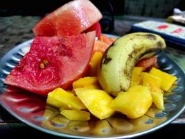 Plate with different fruits on kitchen table photo