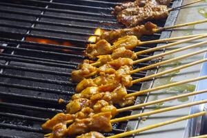 asiático cocina, Malasia pollo satay Cocinando en un caliente carbón parrilla. foto