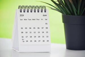 junio 2024 escritorio calendario con en conserva planta en un escritorio con verde antecedentes. foto