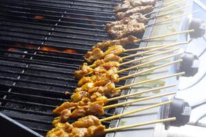 asiático cocina, Malasia pollo satay Cocinando en un caliente carbón parrilla. foto