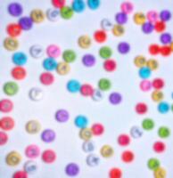 Blurry out of focus photo of alphabet, colorful round numbers, colorful round letters on white background