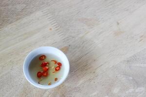 taza de tailandés pescado salsa y chile en de madera mesa foto