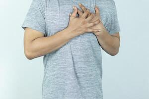 asian man pressing chest with painful expression. Severe heartache, having a heart attack or painful cramps, heart disease. photo