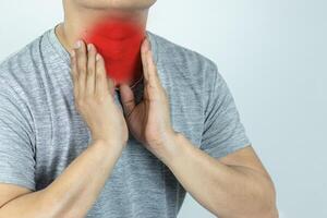 Asian man touching neck with hand because suffering from sore throat photo