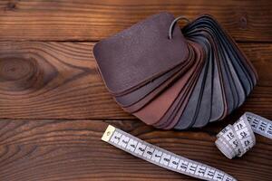 Leather samples for shoes and measuring tape on dark wooden table. photo