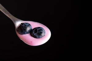 Tasty fresh blueberry yoghurt shake dessert in metal spoon black dark background. photo