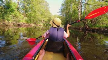 retour arrière vue de femme dans la vie gilet et net chapeau kayak dans magnifique Lituanie campagne rivière - zemeina. action caméra pov de fille pagayer sur canoë bateau dans peu profond des eaux video