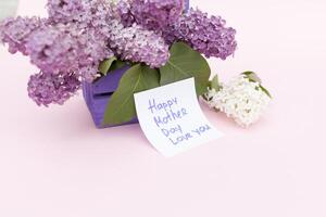 Beautiful bouquet of purple lilac and card on purple paper background photo