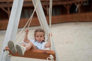 Playful kid swinging swing. Joyful little girl play having fun playground summertime photo