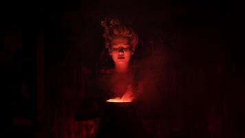 Halloween Witch with cauldron. Beautiful young woman conjuring, making witchcraft photo