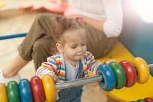 A little girl with two tails in a striped blouse plays a summer sunny day in the playground photo