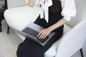 un japonés mujer mecanografía ordenador portátil por remoto trabajo en el oficina sin rostro composición foto