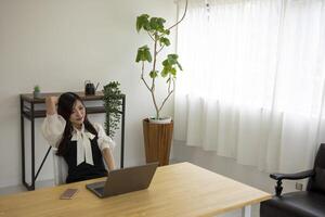 un relajado japonés mujer por remoto trabajo en el pequeño oficina foto