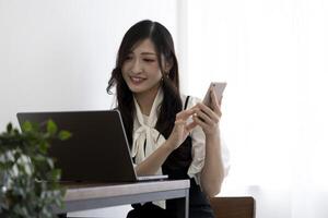 A Japanese woman checking smartphone by remote work in the small office photo
