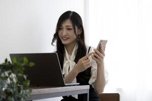 A Japanese woman checking smartphone by remote work in the small office photo
