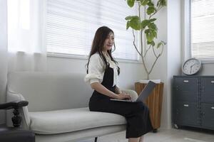 un japonés mujer comprobación teléfono inteligente por remoto trabajo en el hogar oficina foto