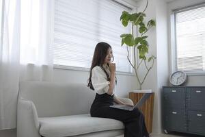 un japonés mujer comprobación teléfono inteligente por remoto trabajo en el hogar oficina foto