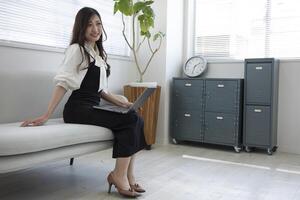 un japonés mujer comprobación teléfono inteligente por remoto trabajo en el hogar oficina foto