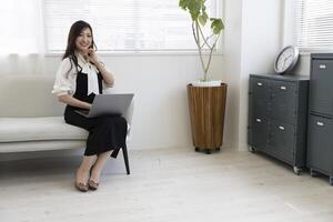 un japonés mujer comprobación teléfono inteligente por remoto trabajo en el hogar oficina foto