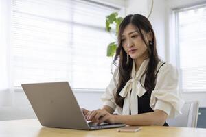 un trabajando japonés mujer por remoto trabajo en el hogar oficina de cerca foto