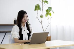 un trabajando japonés mujer por remoto trabajo en el hogar oficina de cerca foto