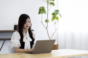 un trabajando japonés mujer por remoto trabajo en el hogar oficina de cerca foto