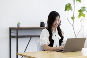 un trabajando japonés mujer por remoto trabajo en el hogar oficina de cerca foto