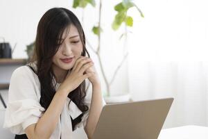 un trabajando japonés mujer por remoto trabajo en el hogar oficina de cerca foto