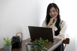 un trabajando japonés mujer por remoto trabajo en el hogar oficina de cerca foto