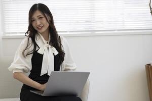 un trabajando japonés mujer por remoto trabajo en el hogar oficina de cerca foto