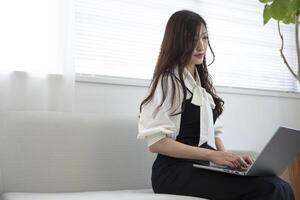 un trabajando japonés mujer por remoto trabajo en el hogar oficina de cerca foto