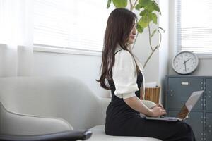 un trabajando japonés mujer por remoto trabajo en el hogar oficina de cerca foto