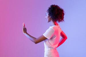 Curly-haired woman gestures at unseen interface, colorful backdrop photo