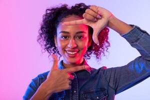 Happy black woman making frame gesture with hands, colorful background photo