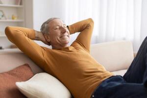 Relaxed elderly man reclining on couch at home photo