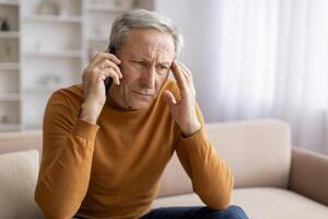 Distressed senior man have phone conversation at home, copy space photo