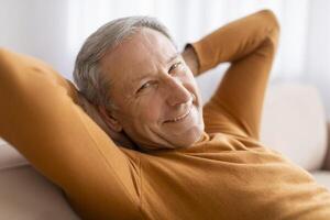 Closeup of happy senior man chilling on sofa at home photo