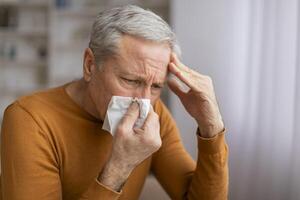 Sick senior man sneezing and touching his head photo