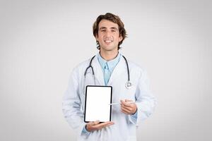 Cheerful male doctor presenting blank tablet screen photo