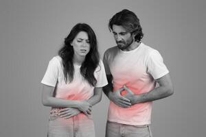 A monochrome image of a man and a woman in white t-shirts, both with hands on their stomachs photo