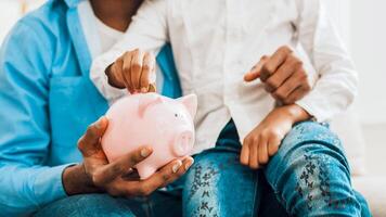 Girl and father putting coin into piggy bank photo