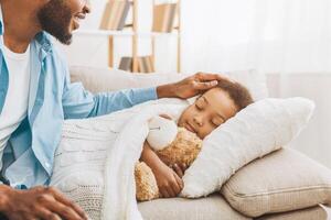 Caring father looking at sleeping daughter, sitting nearby photo