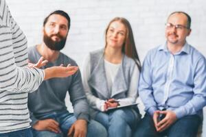 Rehab group listening to woman introducing herself at therapy photo