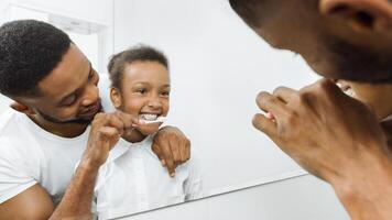 Caring father brushing daughter's teeth in the bathroom photo