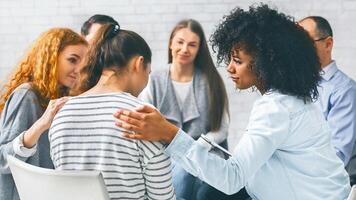 Addicted people comforting woman at psychotherapy session photo