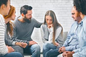 Concerned patients comforting depressed woman in rehab group photo